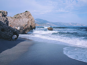 Rugged coastal landscape with waves crashing on sandy beach