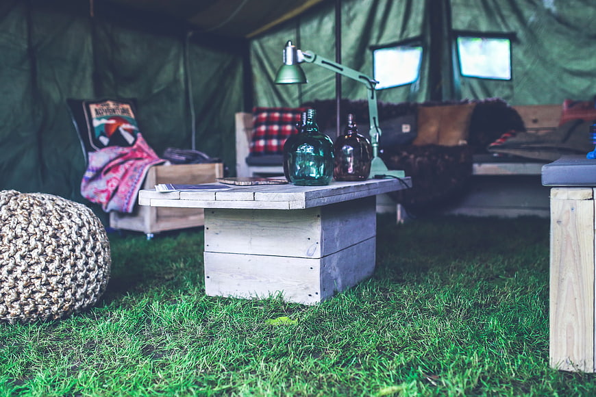 Cozy glamping tent interior with wooden furniture and green decor