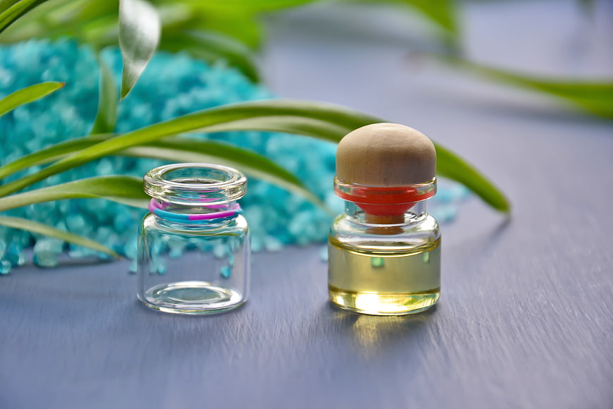 Essential oil bottles with sea salt and green leaves