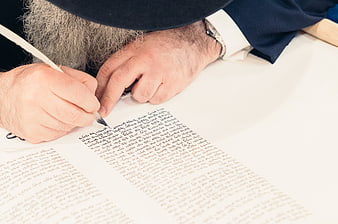 Close-up of man writing Arabic calligraphy with quill
