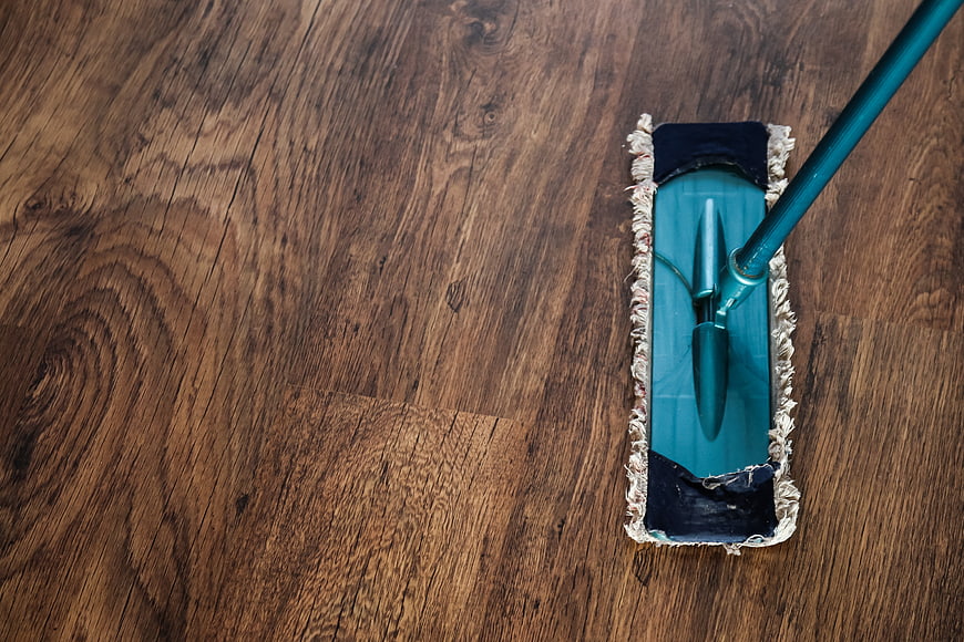 Top-Down View of Teal Mop Cleaning Dark Wooden Floor