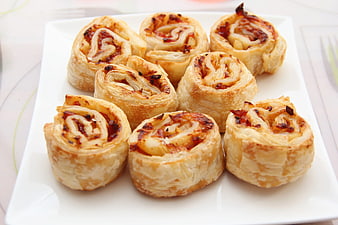 Golden puff pastry pinwheels on white square plate