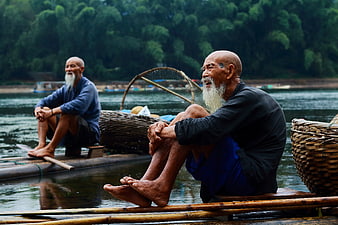 Two elderly fishermen resting on bamboo raft