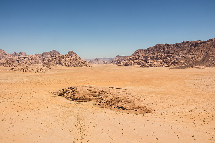 Vast Arid Desert Landscape With Erosion Rock Formations And Blue Sky