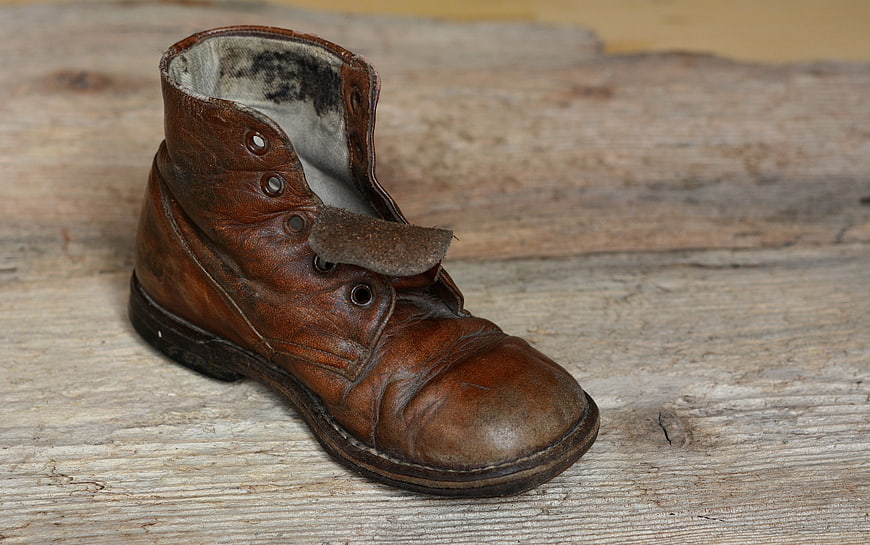 Vintage Worn Brown Leather Boot on Weathered Wooden Surface