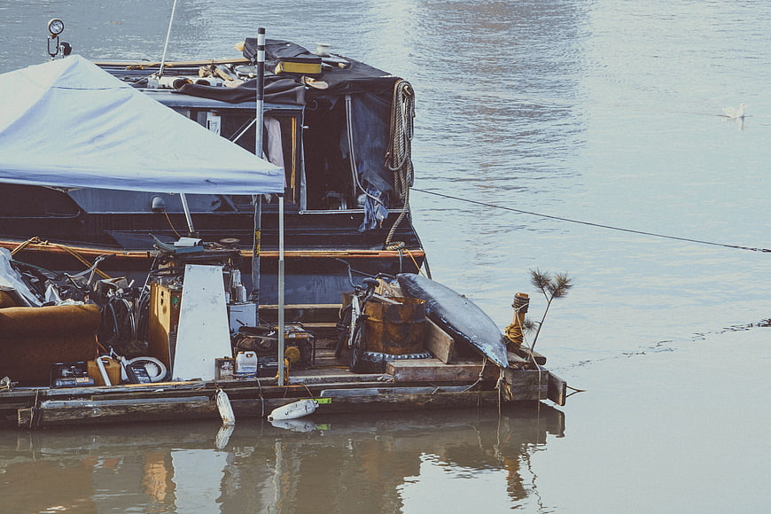 Cluttered Houseboat Docked on Calm River Water
