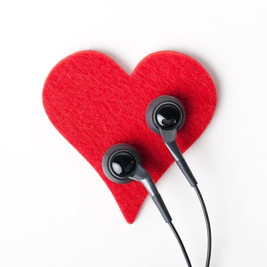 Red felt heart with black earphones on white background