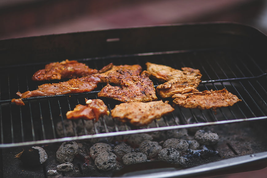 Seasoned pork steaks grilling over charcoal