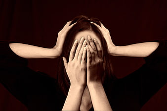 Woman Covering Face in Distress Against Dark Background