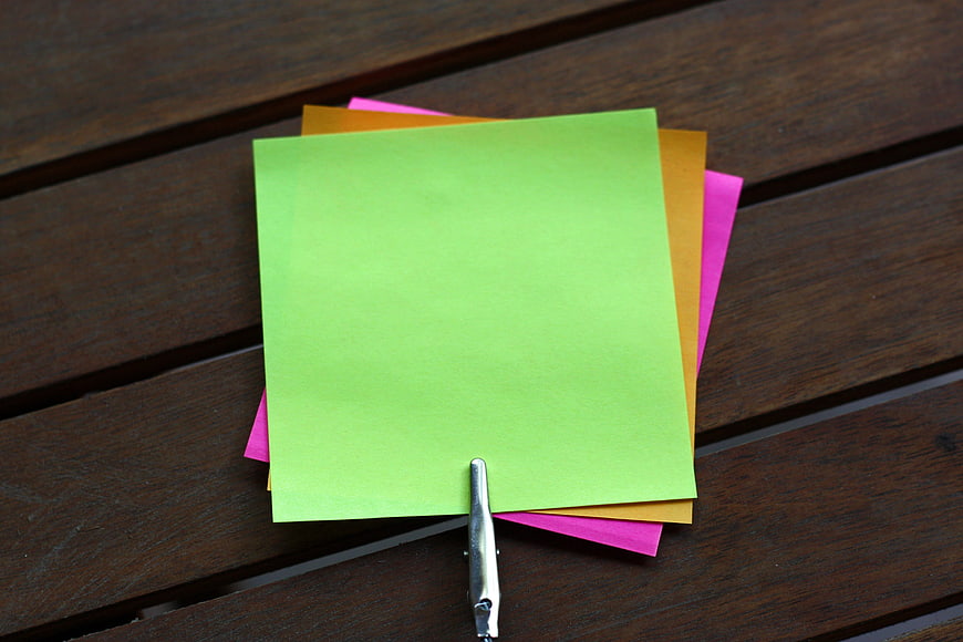 Colorful blank sticky notes clipped on wooden table