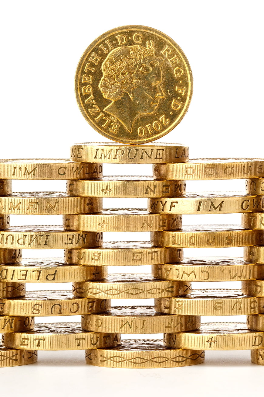 Gold coins stacked in a grid with a single coin balanced on top