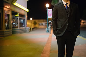 Man in Suit Standing on City Street at Night