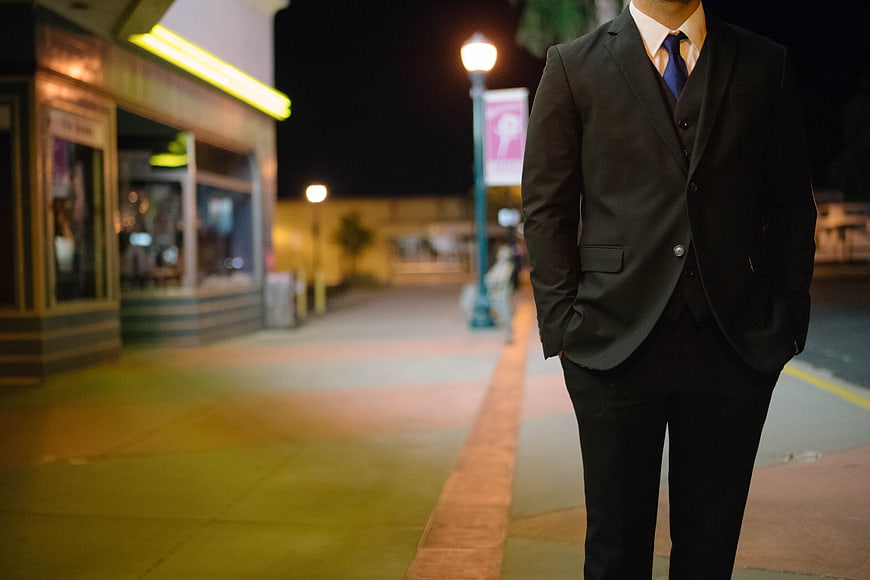 Man in Suit Standing on City Street at Night