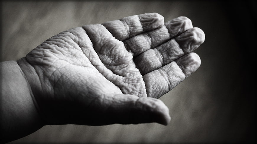 Close-up of wrinkled elderly hand in black and white