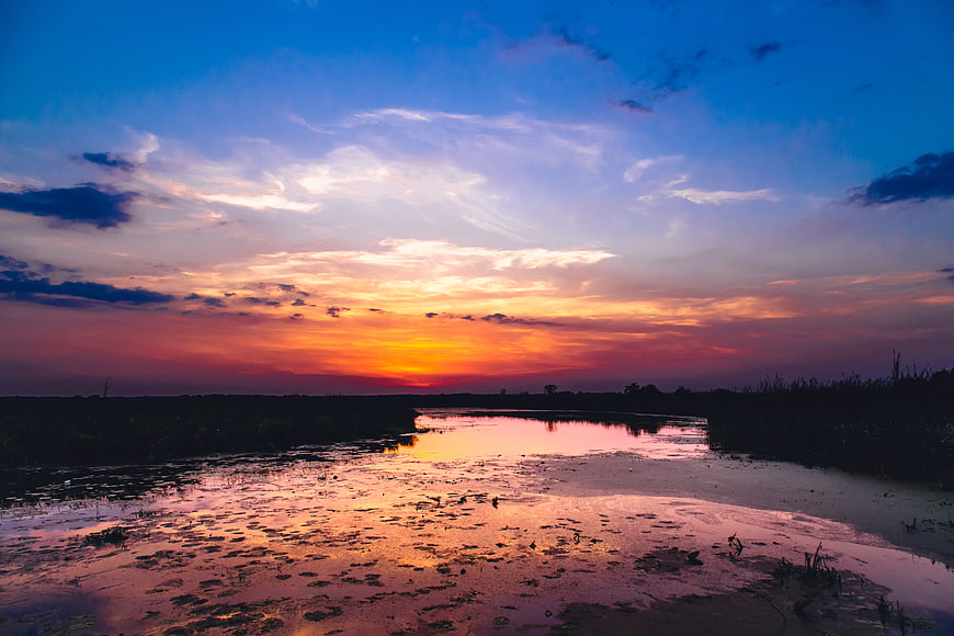 Vibrant Sunset Over Marshy River Landscape