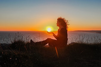 Woman Silhouette Holding Sun Over Ocean Sunset