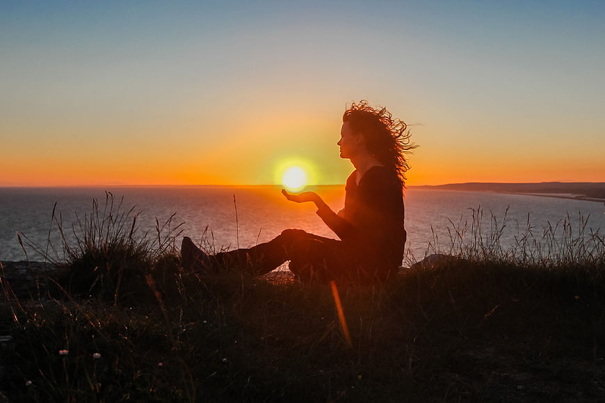 Woman Silhouette Holding Sun Over Ocean Sunset
