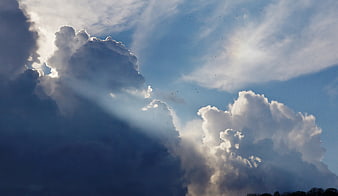 Dramatic Sun Rays Breaking Through Clouds in Blue Sky