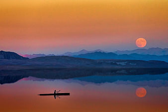 Silhouette of Man Kayaking on Lake at Sunset with Moon