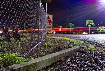 Night long exposure of chain link fence and traffic light trails