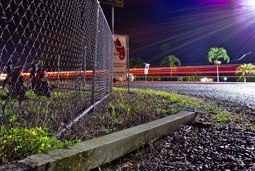 Night long exposure of chain link fence and traffic light trails