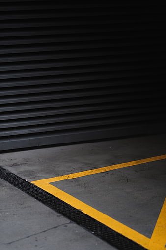 Dark industrial garage floor with yellow safety lines and metal shutter
