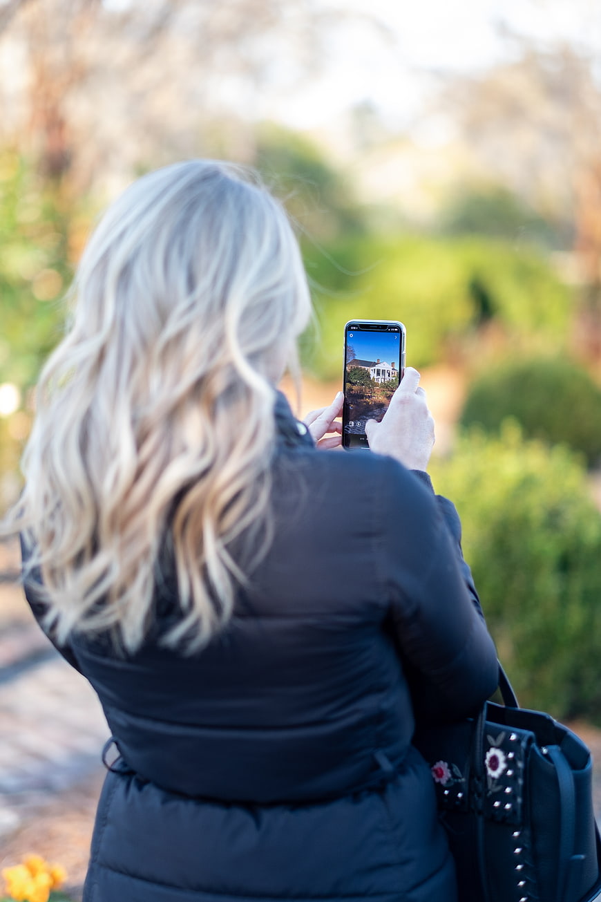 Woman Taking Photo of House with Smartphone in Garden