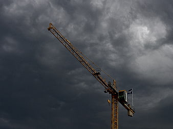Yellow Construction Crane Against Dark Stormy Clouds