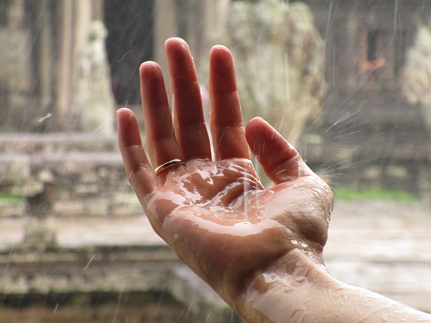 Hand catching raindrops at ancient temple ruins