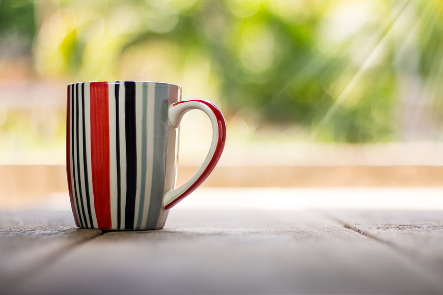 Striped Ceramic Coffee Mug on Wooden Table with Bokeh Background