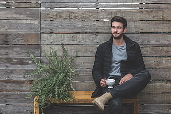 Man Sitting on Wooden Bench with Coffee and Plant