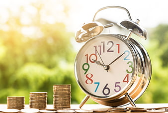Alarm Clock and Stacks of Coins on Wooden Table
