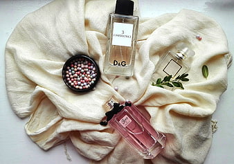 Flat lay of luxury perfume bottles on cream fabric