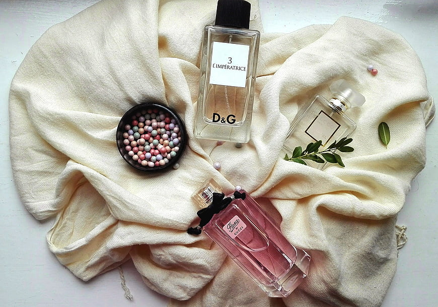 Flat lay of luxury perfume bottles on cream fabric