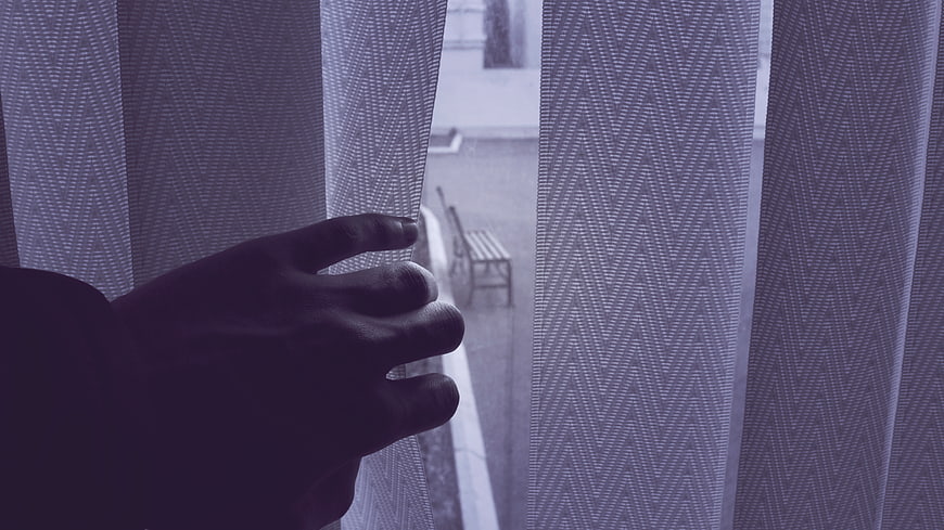 Hand Parting Sheer Curtains to Reveal Rainy Street View