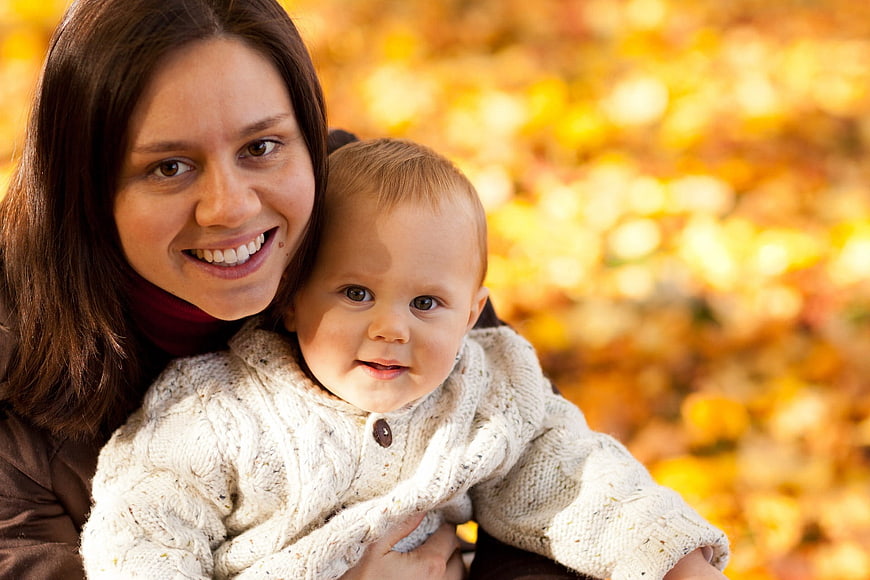 Happy Mother Holding Baby in Autumn Park