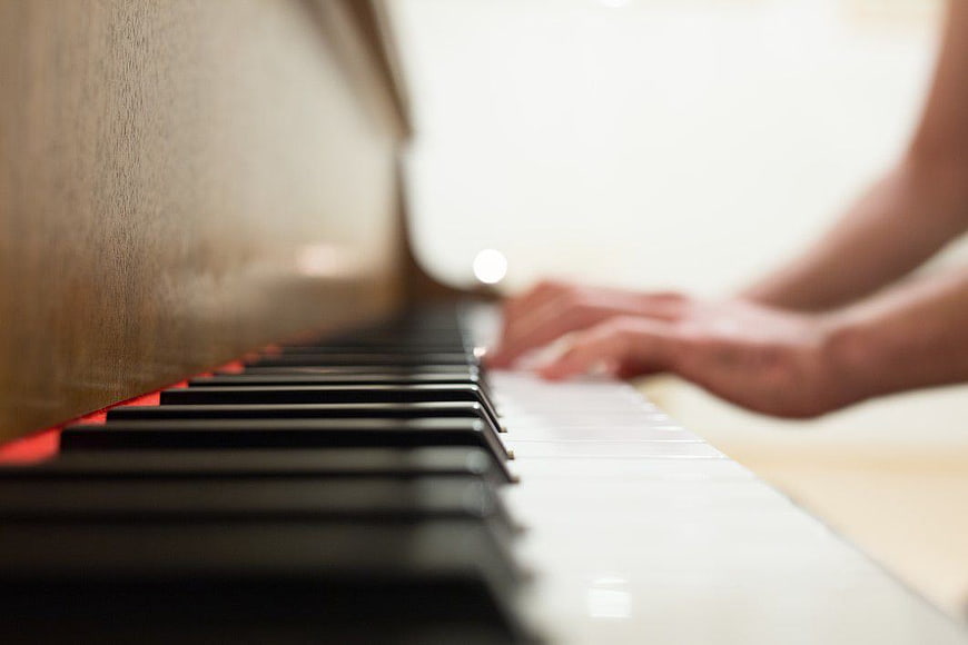 Close-up of hands playing piano keys with shallow depth of field
