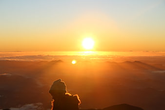 Silhouette of hiker watching sunrise over mountain clouds