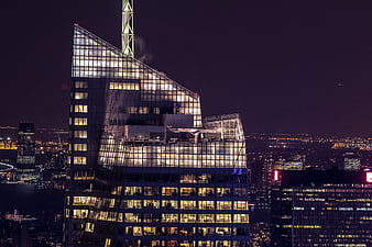 Illuminated modern skyscraper at night with city skyline background
