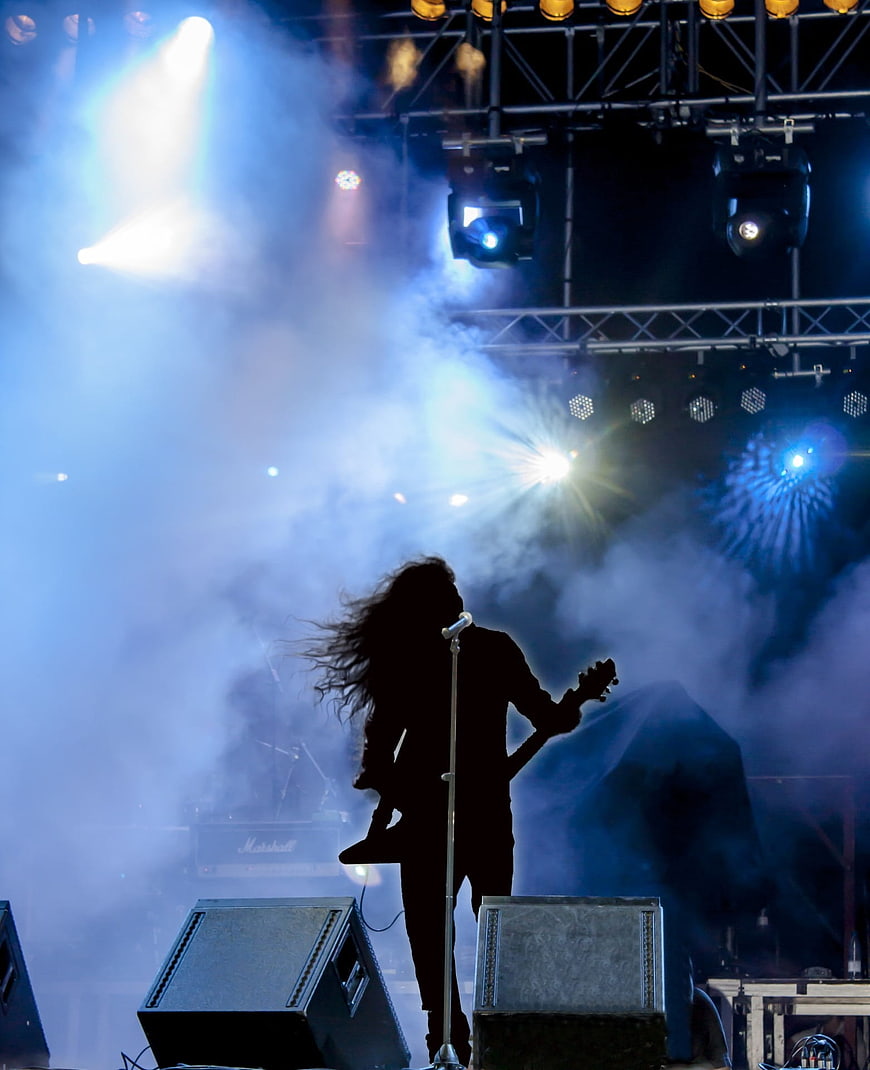 Silhouette of Rock Guitarist Performing on Stage with Blue Lights