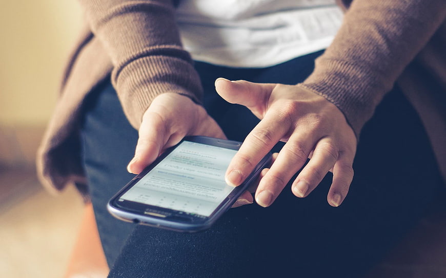 Close-up of hands using smartphone while sitting