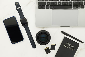 Flat lay of photography gear, laptop, and smartwatch on marble
