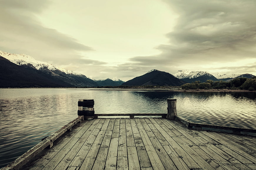Wooden Dock Extending into Lake with Snowy Mountains