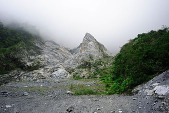 Misty mountain peak with rocky terrain and lush green vegetation