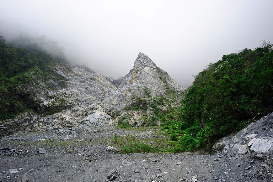 Misty mountain peak with rocky terrain and lush green vegetation