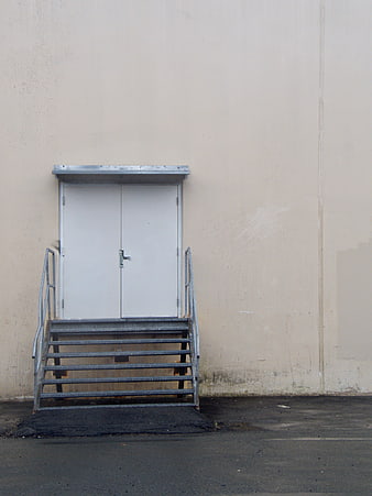 Minimalist white double doors with metal stairs on beige wall