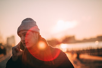 Man talking on smartphone with sunset lens flare