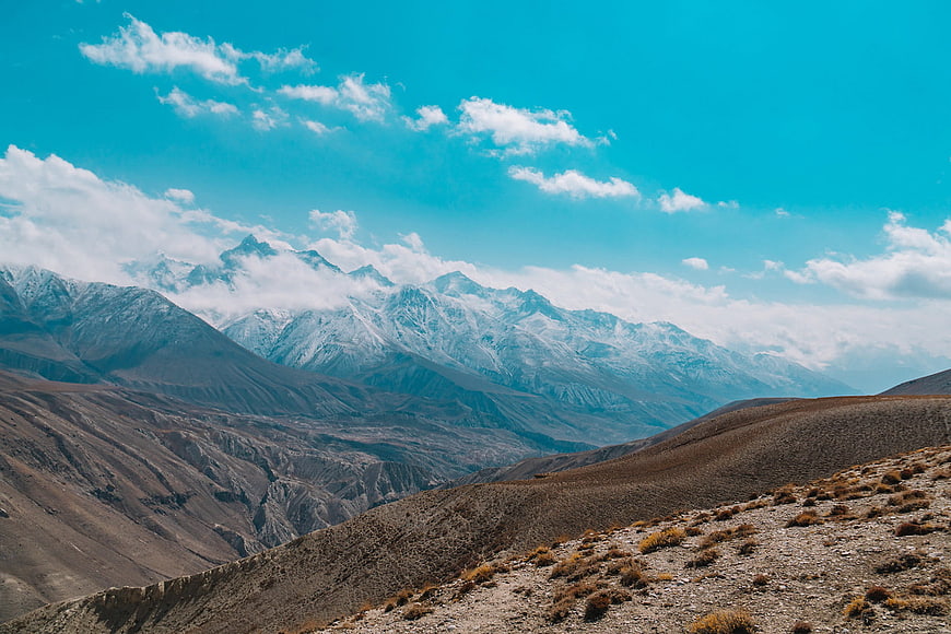 Snow-capped mountains with blue sky and arid foreground