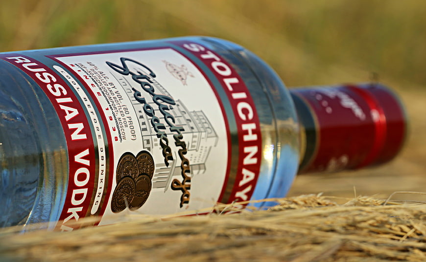 Stolichnaya Russian Vodka Bottle Lying On Hay In Field