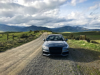 Gray Audi Sedan on Gravel Road in Mountain Landscape